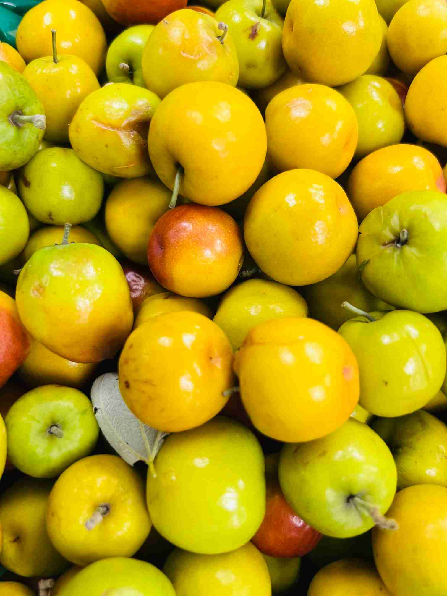 A vibrant pile of fresh yellow and reddish-brown jujubes, known as Boroi, on display at Bismillah Grocery & Meat Market.